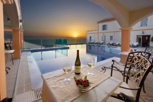 a table with a bottle of wine next to a swimming pool at Belle View Hotel - Sea View & Sunset in Mánganos
