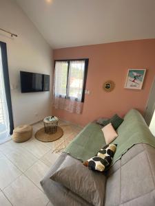 sala de estar con sofá y TV de pantalla plana en Appartement 2 à 4 personnes, Une Pause au Vert en Châteauvieux