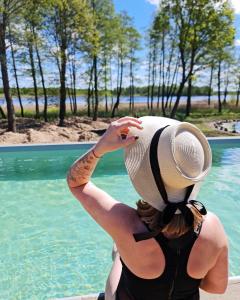 una mujer con un sombrero sentada junto a una piscina en Poilsiaviete Vakaris, 
