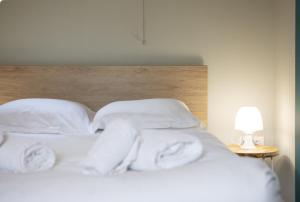 a bed with white sheets and pillows next to a lamp at La péniche de Fabrice avec Jacuzzi privatif in Strasbourg