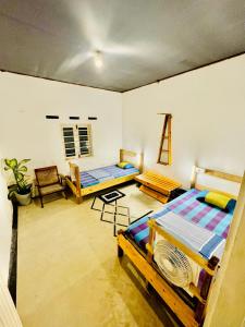 a room with two beds and a table and chairs at Madiha Hostel by Land of Rizka in Matara
