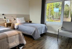 a bedroom with a bed and a chair and a window at Aux Portes du Soleil in Baie-Saint-Paul