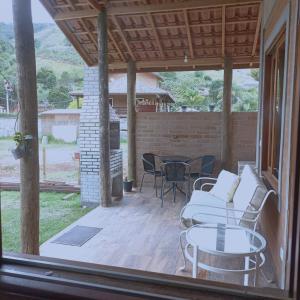 eine abgeschirmte Veranda mit einem Tisch und Stühlen in der Unterkunft Casa Quinta do Paiol in São Bento do Sapucaí
