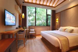 um quarto com uma cama, uma secretária e uma televisão em Mild Spring Boutique Hotel em Huangshan