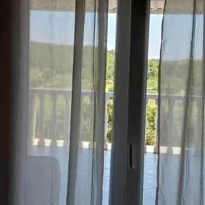 a window with white curtains and a view of a balcony at Apartments Elena & Damir in Vis