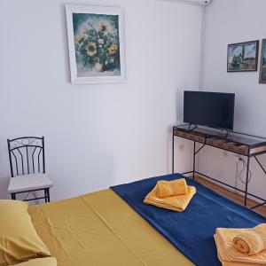 a bedroom with a bed and a desk with a television at Apartments Elena & Damir in Vis
