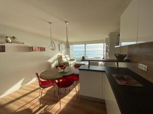 eine Küche und ein Wohnzimmer mit einem Tisch und Stühlen in der Unterkunft RÉF 319 - PLOEMEUR Lomener bel appartement T3 balcon vue mer avec ascenseur in Ploemeur