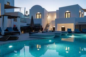 a villa with a swimming pool in front of a house at CUORE SANTO SUITES in Fira