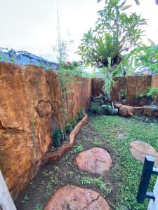 un jardín con una pared de piedra y algunas plantas en Candy home stay en Klungkung