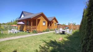 a wooden cabin with a table and chairs in the grass at Zacisze in Sarbinowo