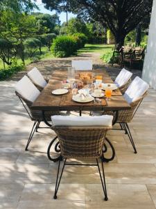 a wooden table with wicker chairs and a table with food at L' Esmerand in Cotignac