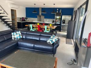 a living room with a black leather couch and a kitchen at Villa privée piscine en Provence in Rougiers