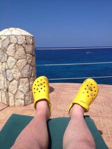 Um homem com sapatos amarelos nos pés a olhar para o oceano. em home sweet home resort em Negril