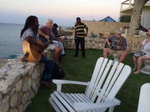 een groep mensen die op een muur gitaar spelen bij home sweet home resort in Negril
