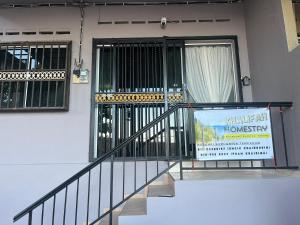 a building with a sign in front of a door at KHALiFAH HOMESTAY in Kampong Bugis