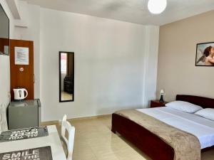 Tomi Apartments في سارنده: غرفة نوم فيها سرير وطاولة فيها