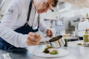 kucharz przygotowujący danie w kuchni w obiekcie Hotel Riederalm w mieście Leogang +37 zdjęć