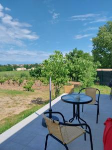 a patio with a table and chairs and a view of a field at la petite maison in Lablachère