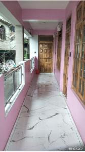 a hallway of a building with pink walls and marble floors at Iqra Explore Hills in Darjeeling