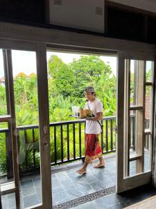 un uomo che cammina su un balcone con un pacchetto di Widya Luxury House ad Ubud
