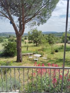 een balkon met een boom en een tafel en banken bij Loft rez de jardin in Forcalquier