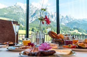 einen Tisch mit Teller mit Speisen und Gläsern Wein in der Unterkunft Hotel Riederalm in Leogang