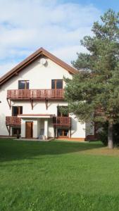 a large white house with a balcony and a tree at Apartmány LehotSKI Guest House in Pavčina Lehota