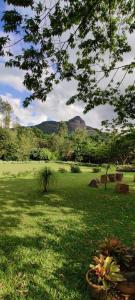 a field of green grass with mountains in the background at The Sattva Nature Retreat in Avathi