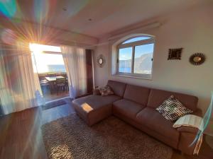 a living room with a brown couch and a window at Blue Sky Xlendi in Xlendi