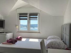 a white bedroom with a bed and a window at Apartments Ploka in Trogir