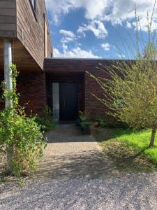 a brick building with a black door on it at Maison spacieuse avec piscine au sel proche grand stade in Sainghin-en-Mélantois