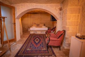 a room with a bed and a chair and a rug at Sur Cave Hotel in Ürgüp