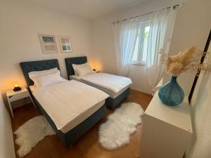 1 dormitorio con 2 camas y un jarrón en el suelo en Luxury apartments Nikolina Sea&City view en Makarska