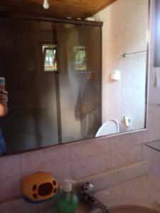 - un miroir au-dessus d'un lavabo dans la salle de bains dans l'établissement Chalé Maringá, à Bocaina de Minas