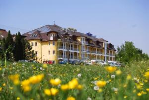 a large yellow building with a field of flowers at Hotel Venus in Zalakaros