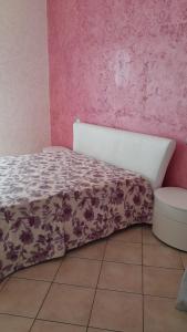 Cama en habitación con pared de color rosa en Anna's apartment - Milazzo, en Milazzo