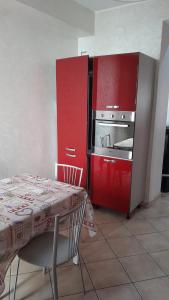 cocina roja con fogones y mesa en Anna's apartment - Milazzo, en Milazzo