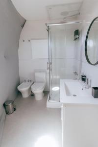a white bathroom with a toilet and a sink at Glamping Puente Blanco in Sierra de la Ventana