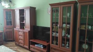 a living room with a tv and wooden cabinets at Apartmán Sofia in Levice