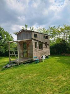 mały drewniany dom na polu z zielonym dziedzińcem w obiekcie Tiny House et yourte sous les Poiriers w mieście Domfront