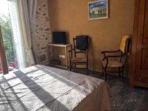 sypialnia z łóżkiem, 2 krzesłami i telewizorem w obiekcie Gîtes des Ecuries de Saint Maurice w mieście Lacapelle-Marival