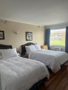 1 Schlafzimmer mit 2 Betten und einem Fenster in der Unterkunft Hotel Motel Le Château in Lac-Mégantic