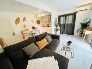 a living room with a black couch and a table at Cabane le Flamant avec jardin, piscine chauffée et parking in Saintes-Maries-de-la-Mer