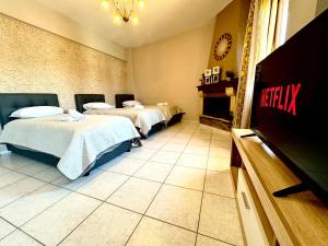 a hotel room with two beds and a tv at George Airport Apartments in Heraklio Town