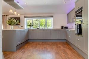 a large kitchen with white cabinets and a large window at Tilly's, a two bedroom holiday retreat with hot tub and views of the pond in Barningham