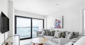 a white living room with a couch and a tv at Luxury stay near O2 and canary wharf in London