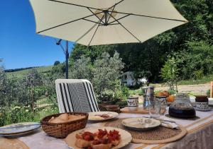 une table avec des assiettes de nourriture et un parapluie dans l'établissement Paradise Agricamp, à Roccastrada