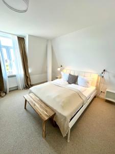 biała sypialnia z dużym łóżkiem i ławką w obiekcie Hotel Villa Klasen w mieście Wenningstedt