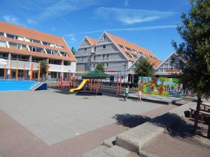 un parque infantil con tobogán en un patio con edificios en Wunderschoenes-freihstehendes-Ferienhaus-an-der-See-Sauna-Strand-Yachthafen-WLAN, en Bruinisse