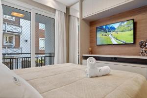 a bedroom with a bed with a television on a wall at Apartamento Loft One 1dorm by Achei Gramado in Gramado